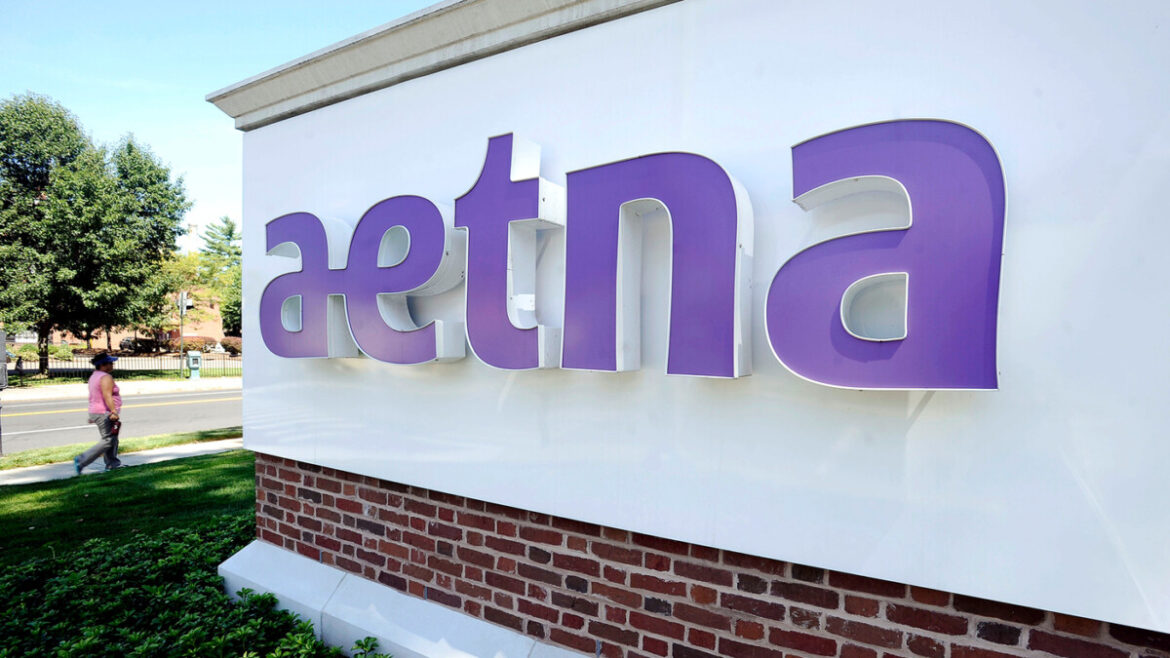 Aetna The logo of Aetna (lower case in purple) is written on a brick wall displayed on a angle.