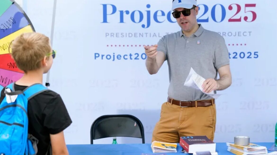 Project 2025 Spencer Chretien, right, talks to a young fairgoer at the Project 2025 tent at the Iowa State Fair, Aug. 14, 2023, in Des Moines, Iowa. (AP Photo/Charlie Neibergall)
